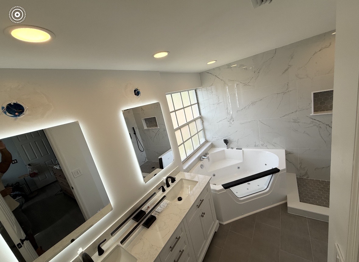 Renovated master bathroom with marble-look tile, jetted tub and LED mirrors