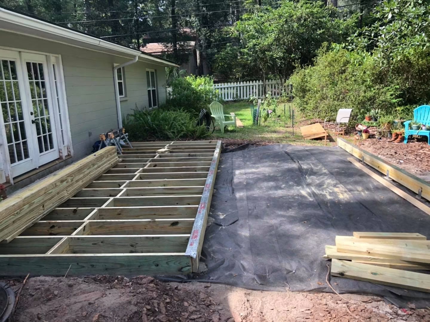Deck build step 2 of 4: pressure-treated joists framed on 16-inch centers spanning the footings, forming the structural skeleton of the deck