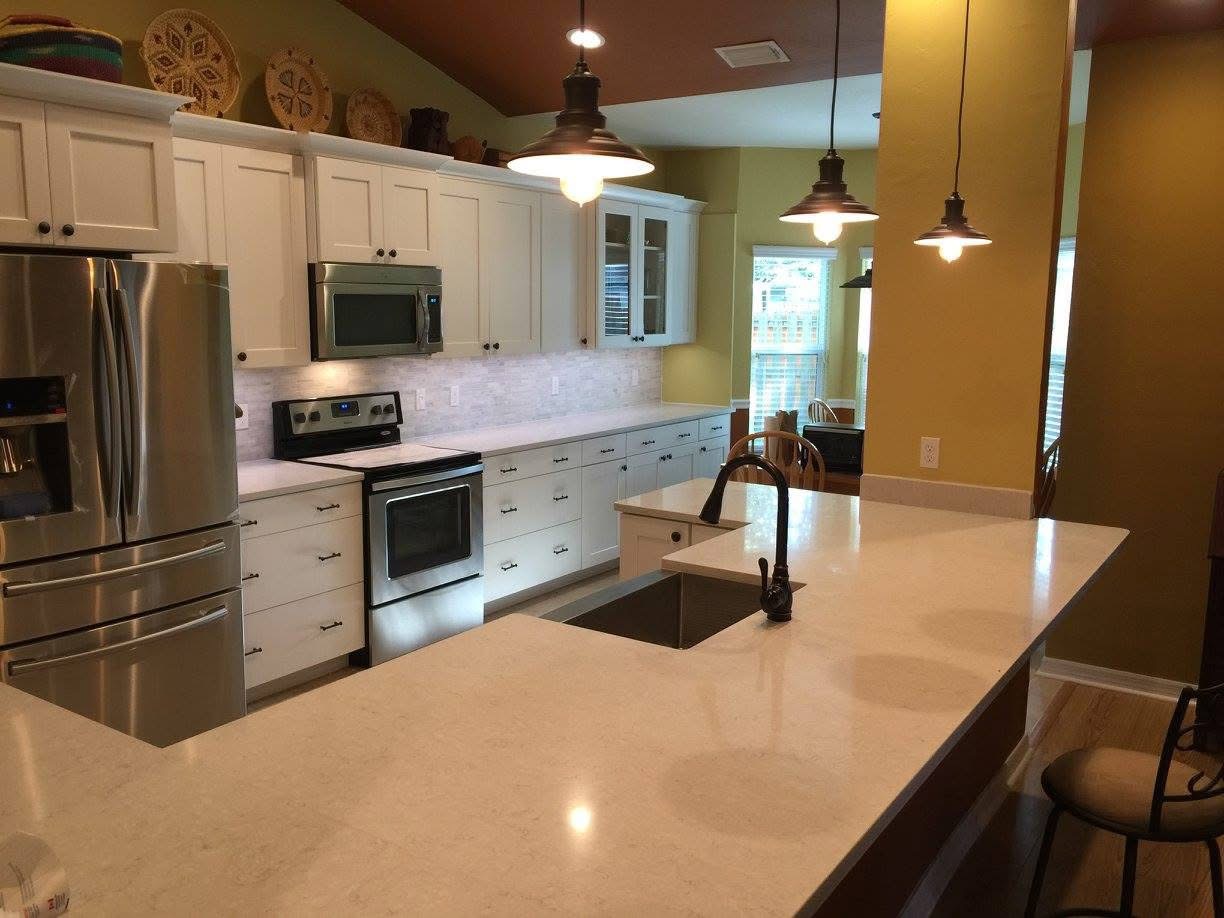 Finished kitchen with quartz island, white shaker cabinets and mosaic backsplash